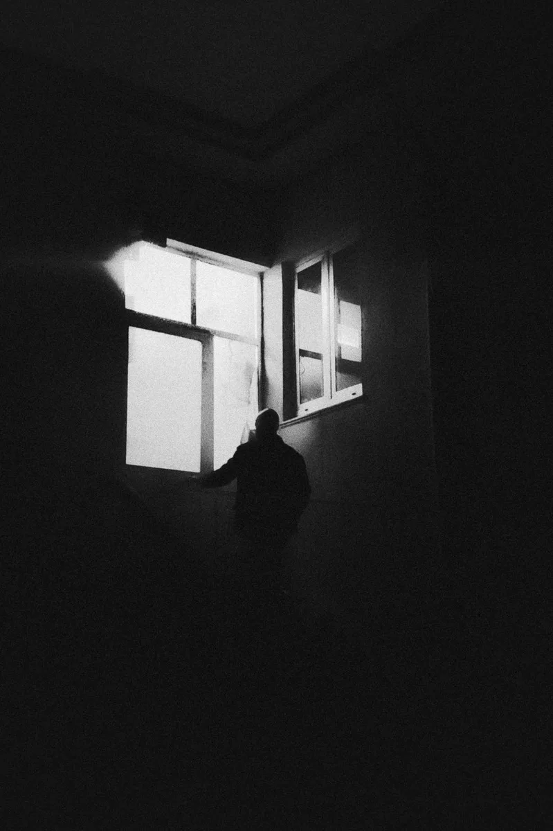 Dunkler Raum mit Person als Silhouette am Fenster