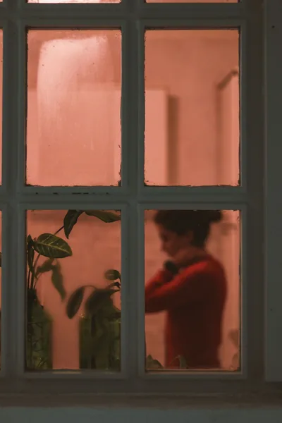 Silhouette einer Frau am Fenster bei Nacht